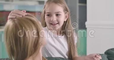 可爱的白种人女孩的特写脸，棕色的眼睛抚摸着母亲`头发，笑着。 有趣的孩子在表达